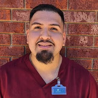 Animal Health Care Center's Veterinary Technician Alex Veterinary Technician Alex wearing maroon scrubs and an ID badge at Animal Health Care Center